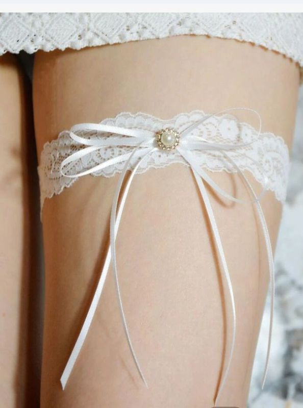 White lace garter with bow and pearl detail around leg — Shona's Lingerie in Annadale, QLD.