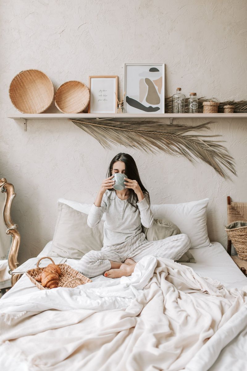 Woman in Pajamas on Bed, Drinking From a Mug, With Breakfast — Shona's Lingerie in Hermit Park, QLD
