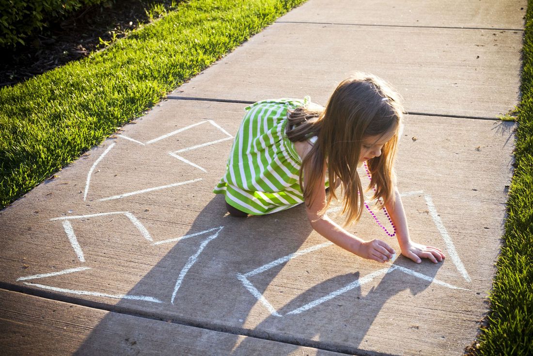 Bambina disegna sul marciapiede