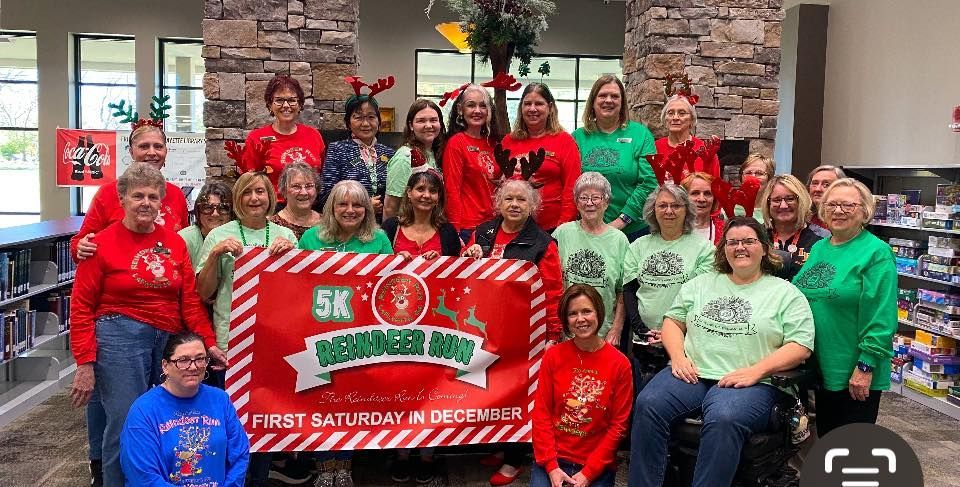 A group of women are posing for a picture in front of a sign.