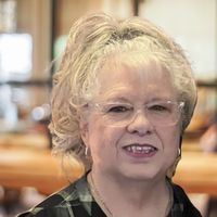 A close up of a woman wearing glasses and smiling.