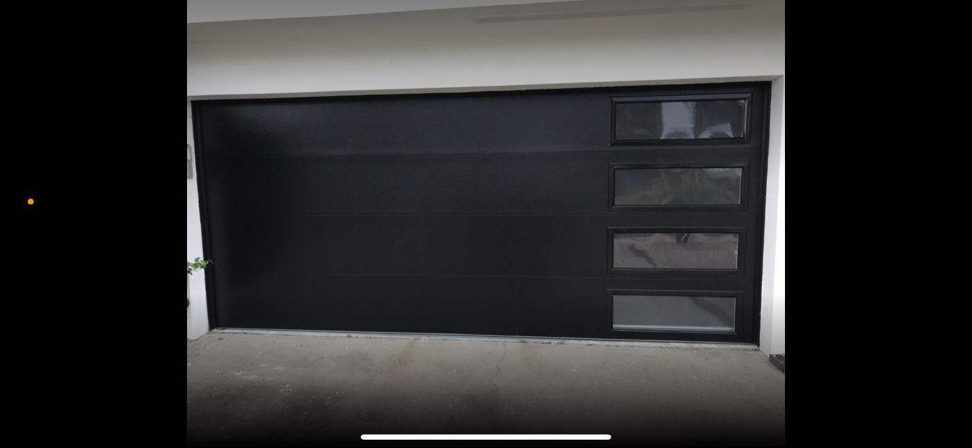 Black garage door with four rectangular windows.