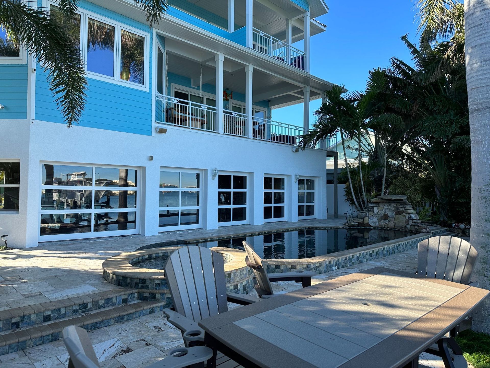 A blue and white house with a pool and patio furniture on a sunny day.