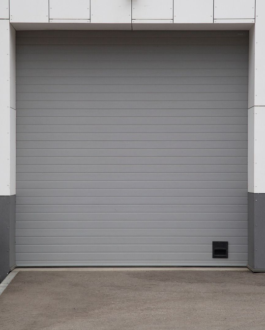 Gray garage door set in a building with white and gray features.