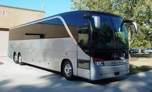 A silver bus is parked in front of a building with the number 07 on it