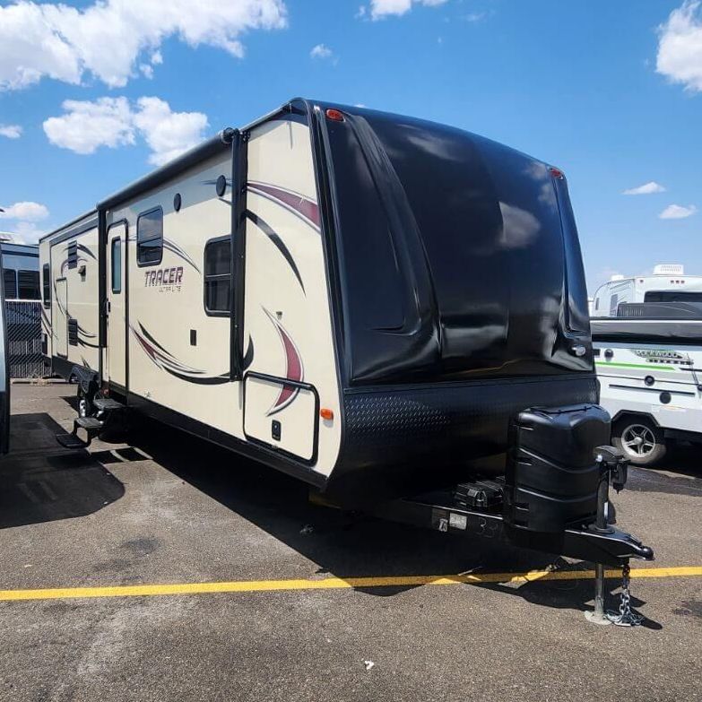 A camper trailer is parked in a parking lot on a sunny day.