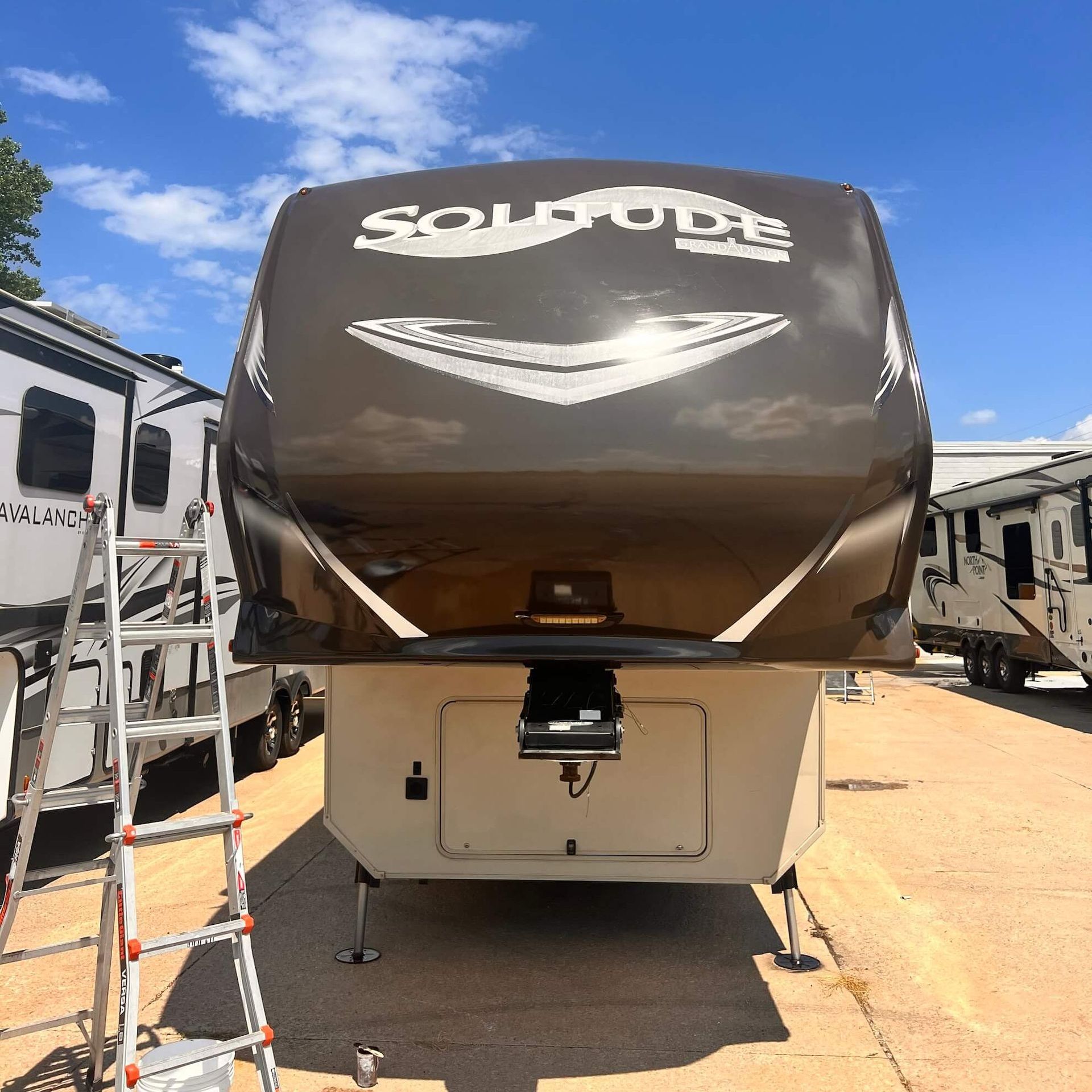 A ladder sits in front of a rv that says sold oute