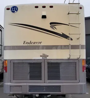 A white endeavor rv with a ladder on the back