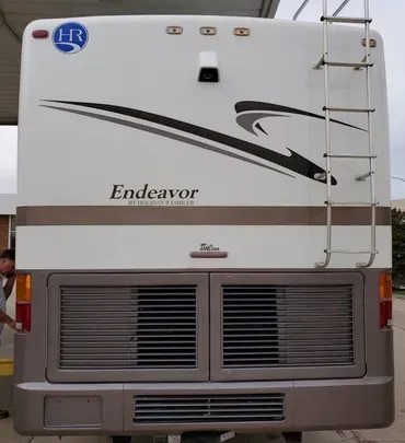 A white endeavor rv with a ladder on the back