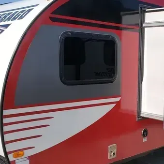 A red and white camper trailer with a large window
