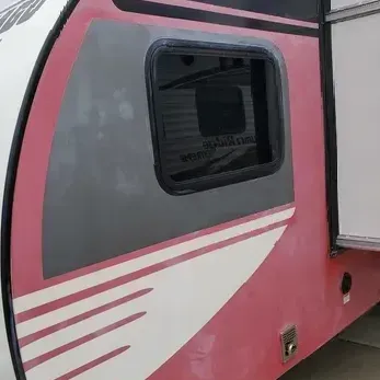 A pink and white trailer with a window on the side.