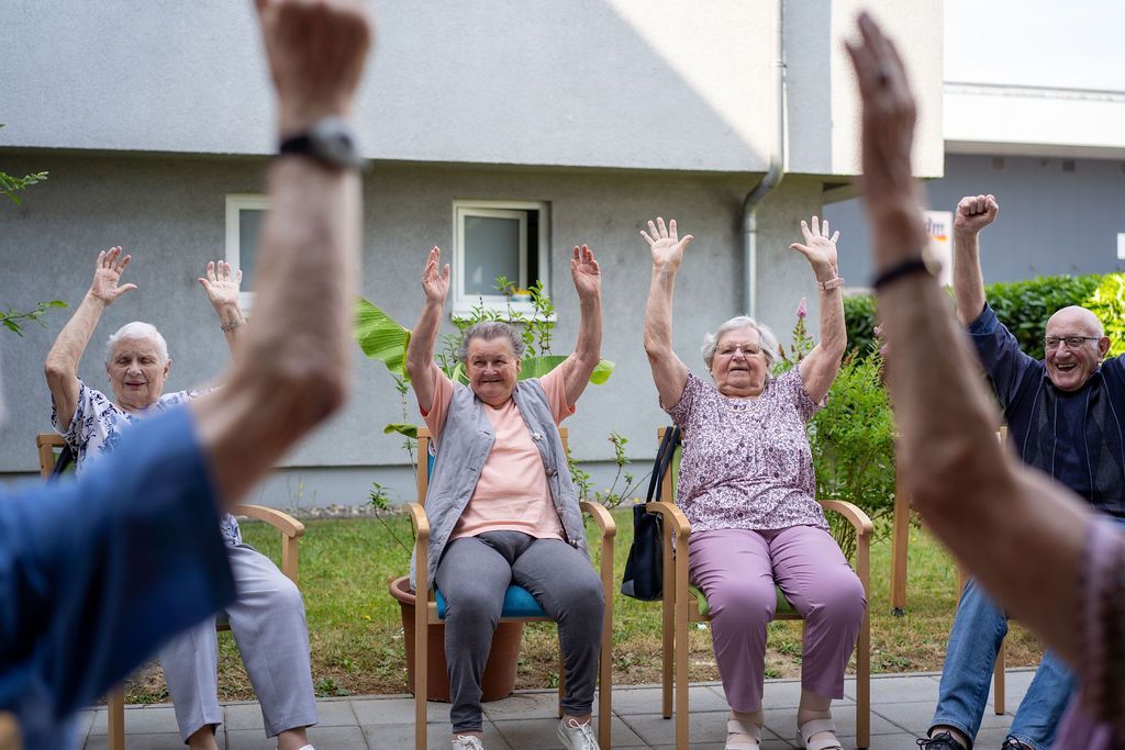 Gäste der Tagespflege St. Elisabeth Bühl machen Gymnastik im Garten.
