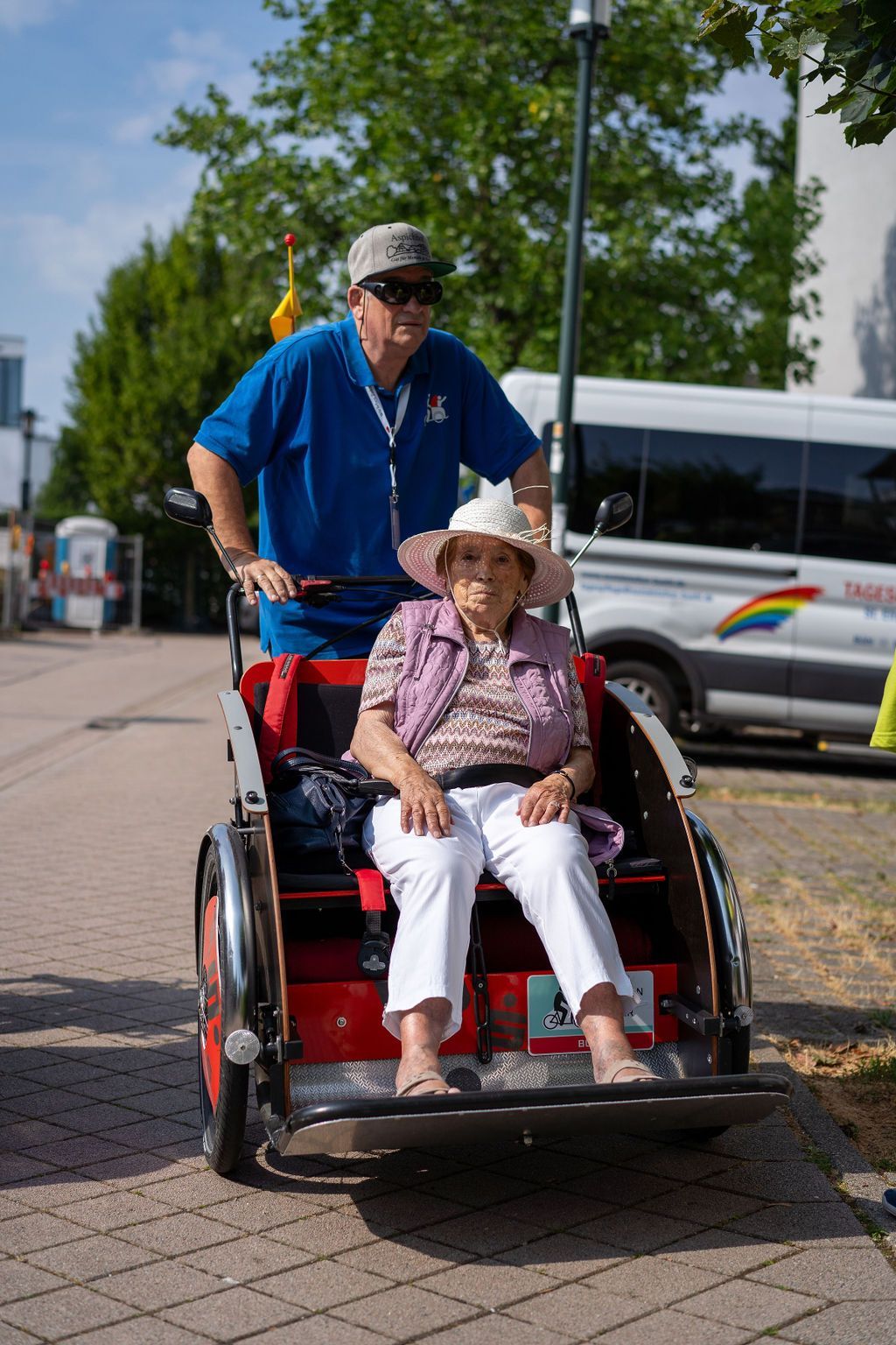 Seniorin wird von Betreuungskraft in Rikscha herumgefahren.