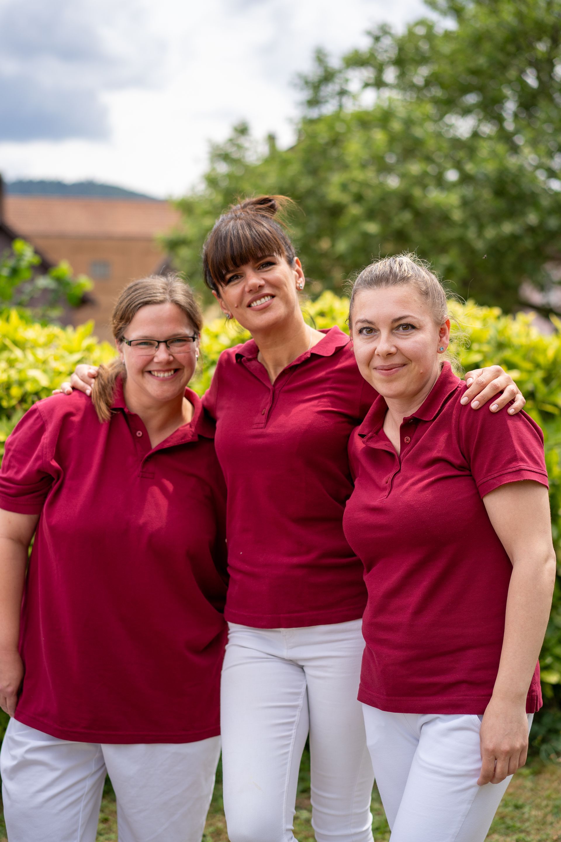 Drei Mitarbeiterinnen der Sozialstation in Dienstkleidung Arm in Arm