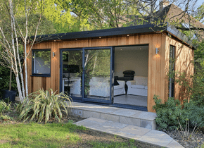 A small wooden house with sliding glass doors and a living room.