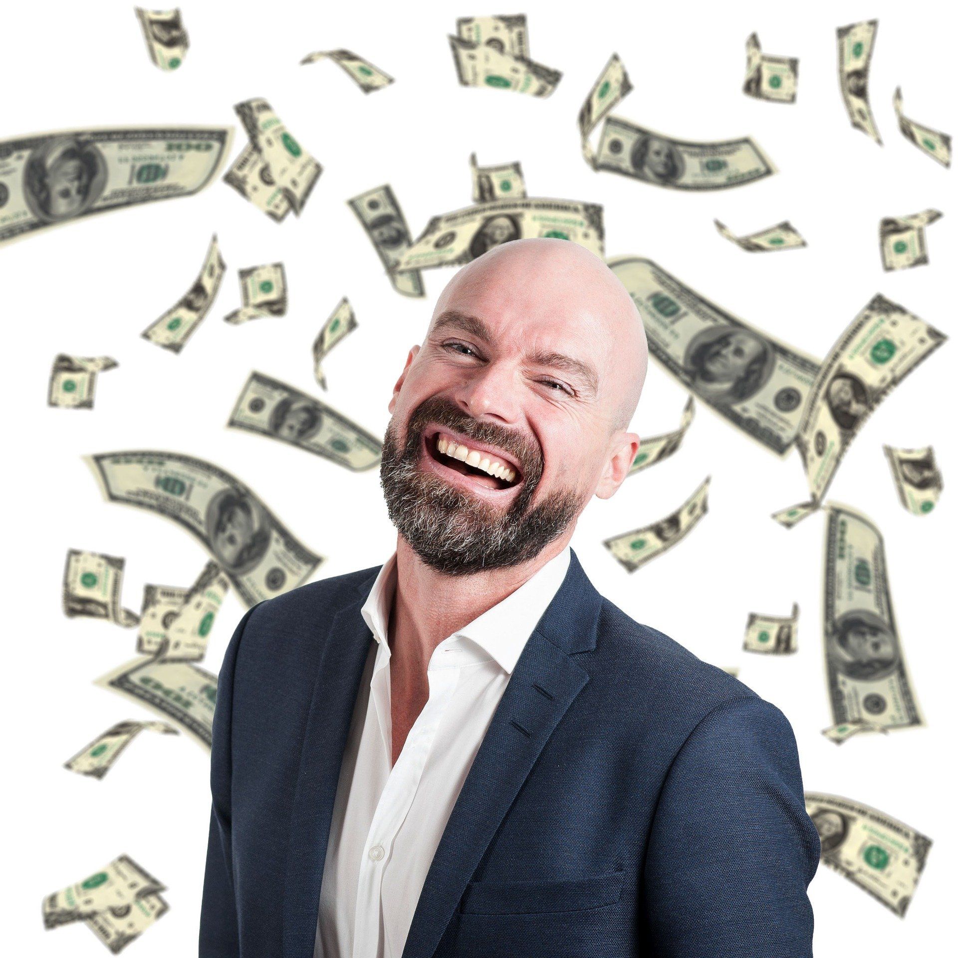 Business man with a large smile is standing around falling money