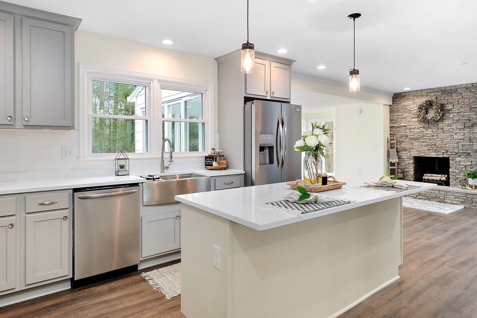 Modern kitchen with a stainless steel refrigerator, island, and stone fireplace.