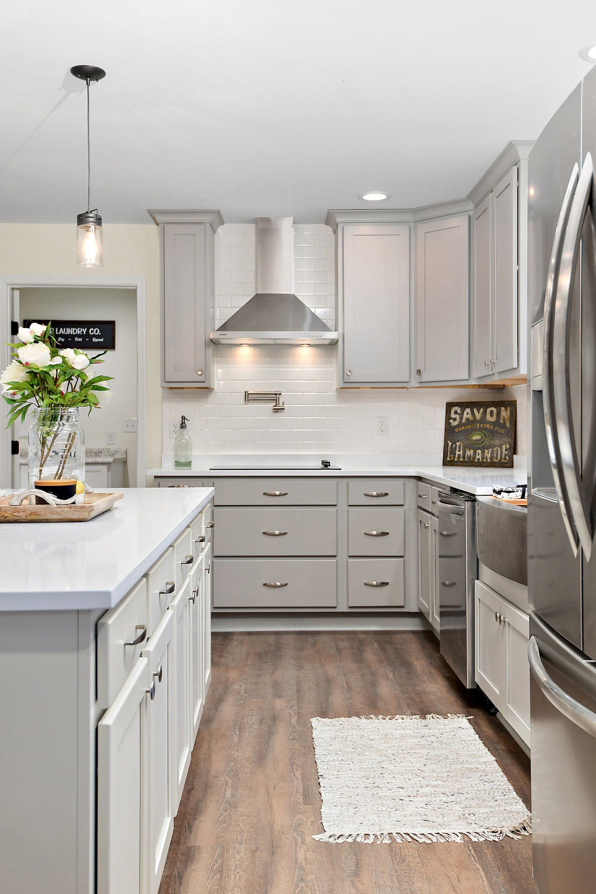 A modern kitchen with gray cabinets, stainless steel appliances, and a white island.