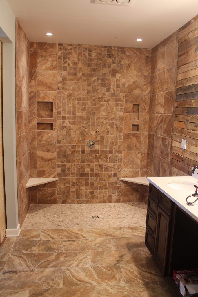 Bathroom with brown tile shower, benches, and vanity; shower has recessed shelves.