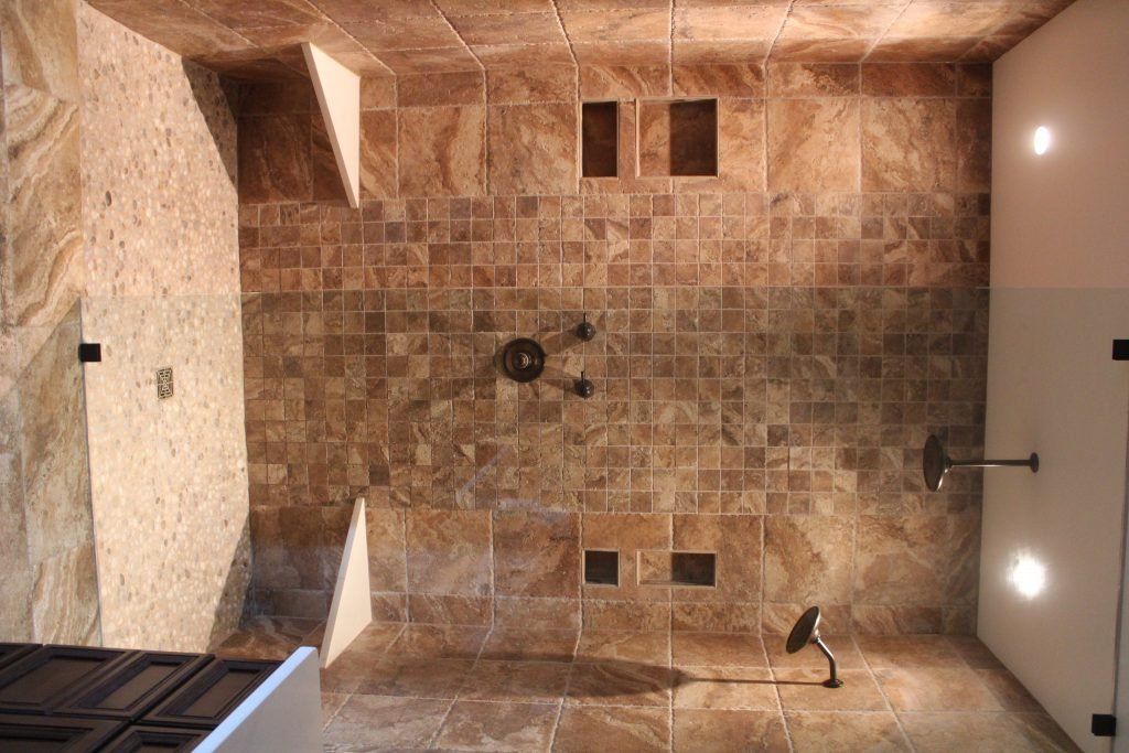 Bathroom with stone tile walls, shower fixtures, and recessed shelving.