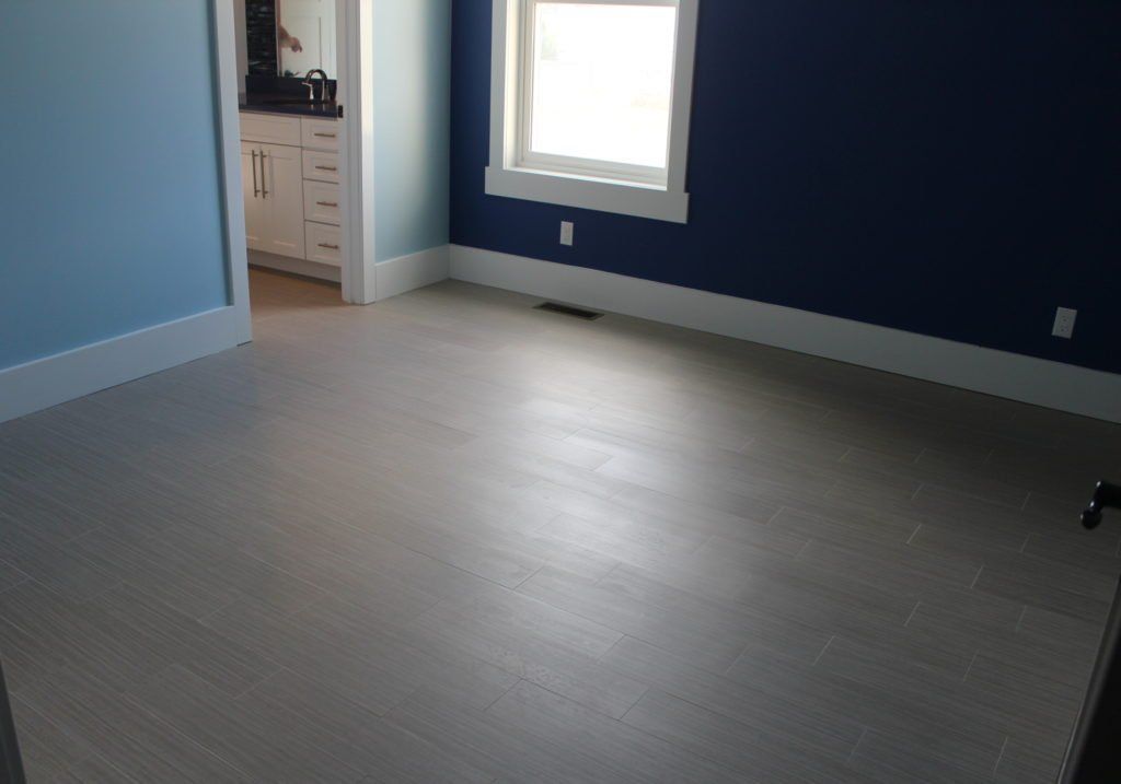 Empty room with light gray wood-look floor, light blue and dark blue walls, and white trim.
