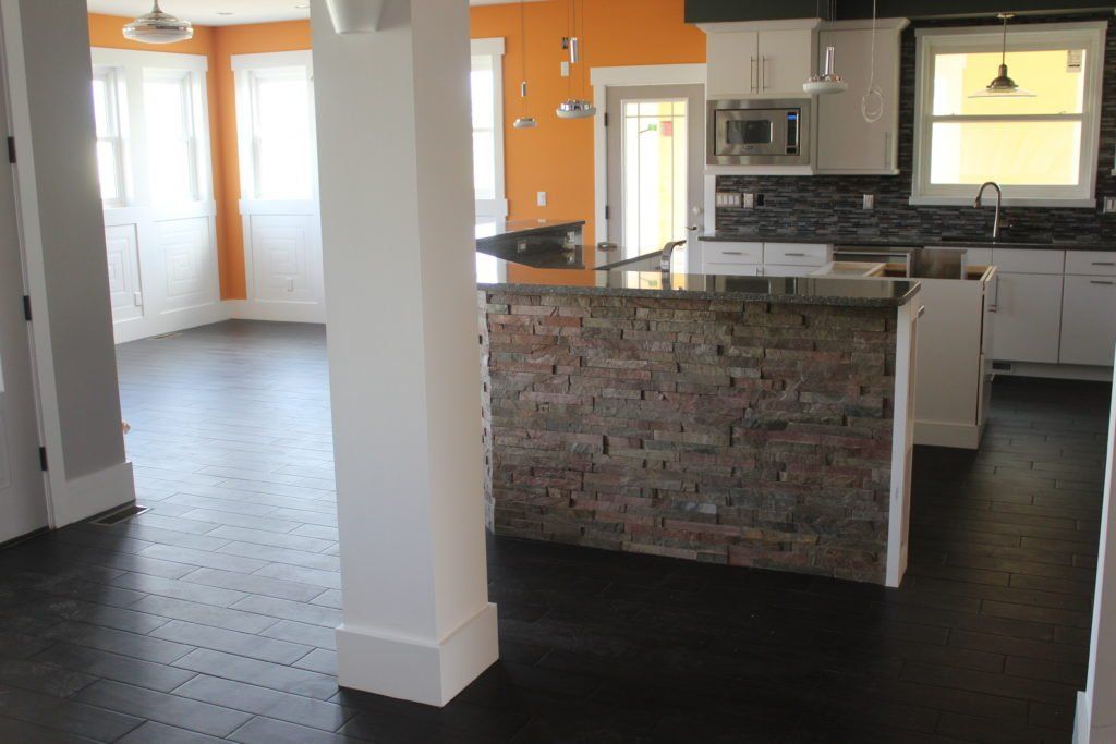 Kitchen with dark wood floors, orange and white walls, stone island.