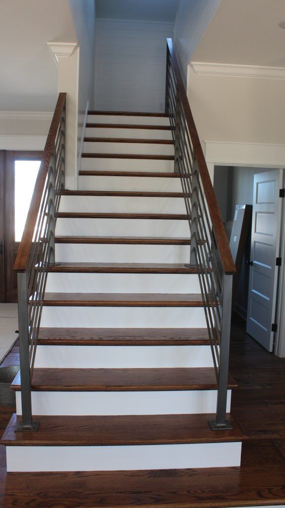 Staircase with wooden steps, white risers, and metal railing. Brown wood handrail, leading up.