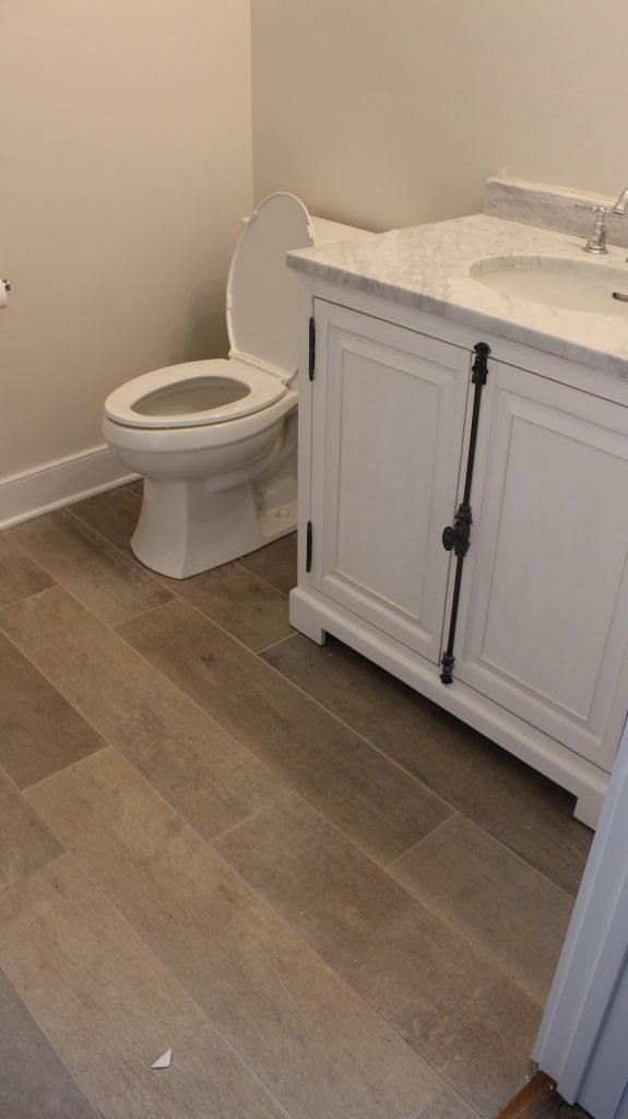 Bathroom with white toilet, vanity, and gray floor tiles.