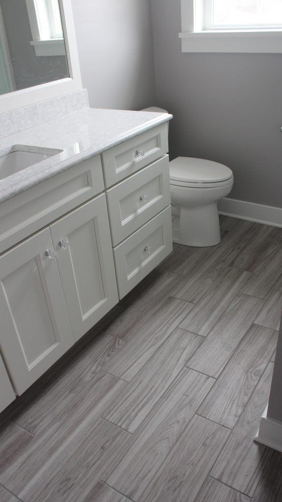 Bathroom with white vanity and toilet, gray floor and walls.