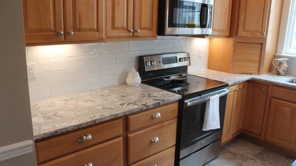 Kitchen with wood cabinets, granite countertops, stainless steel appliances, and white backsplash.
