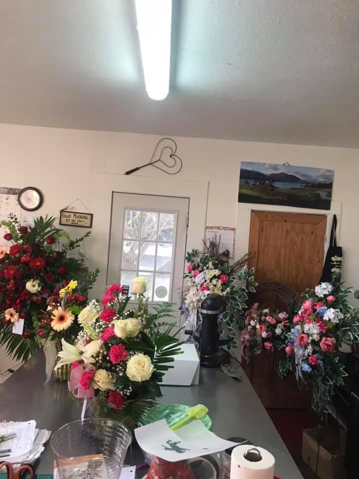Floral shop interior, bouquets on a counter, white walls, overhead light, door, painting, decor.