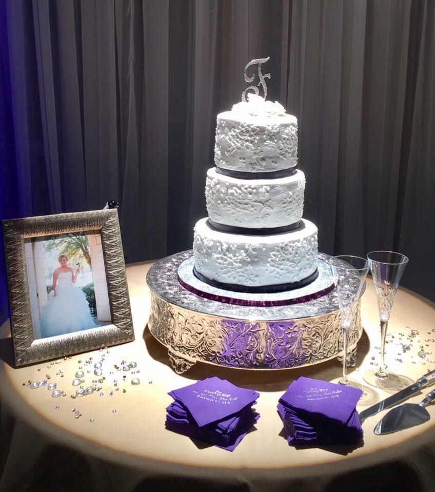 Four-tier white wedding cake with floral design and initial 