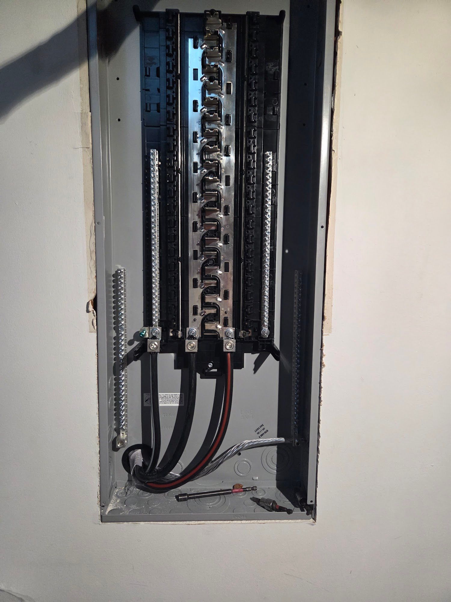 Electrical panel in a wall. Metal box with circuit breakers and wires.
