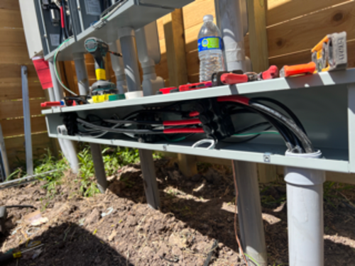 Electrical conduit and junction box under construction outdoors with tools visible.