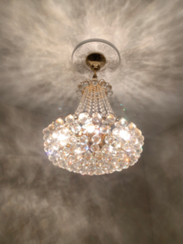 Crystal chandelier hangs from a ceiling, casting light patterns.