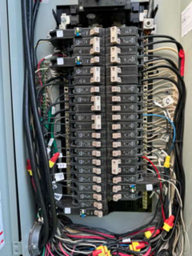 Electrical panel with rows of circuit breakers and wiring.