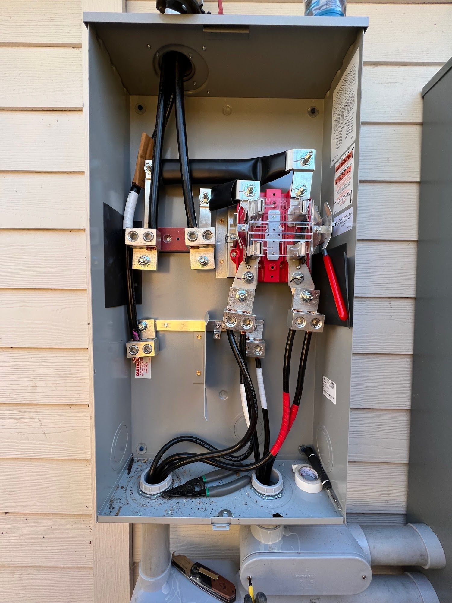 Open electrical meter box with black and red wires connected to terminals.