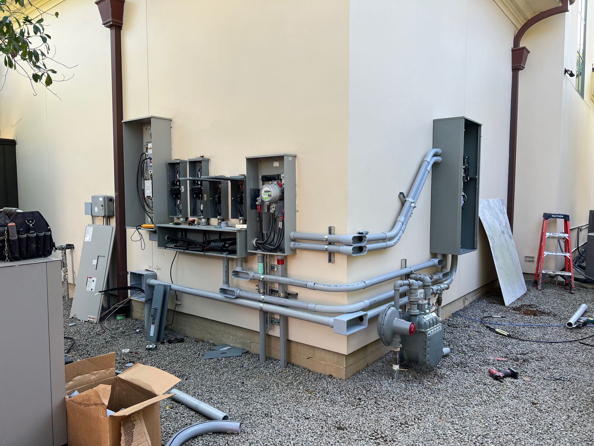 Electrical equipment installed on the outside corner of a building, including conduit, boxes, and a gas meter.