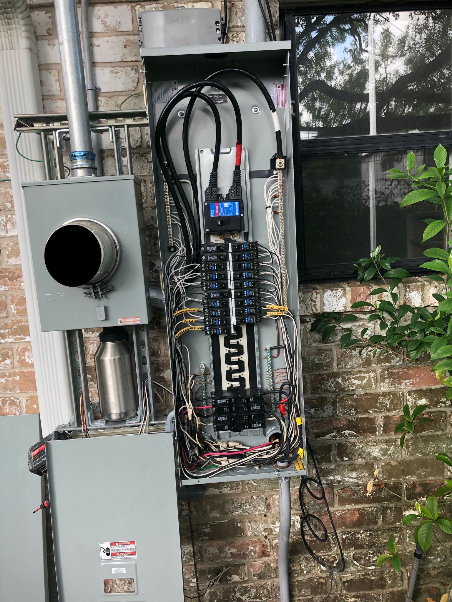 Electrical panel box mounted on a brick wall with conduits and wiring visible.
