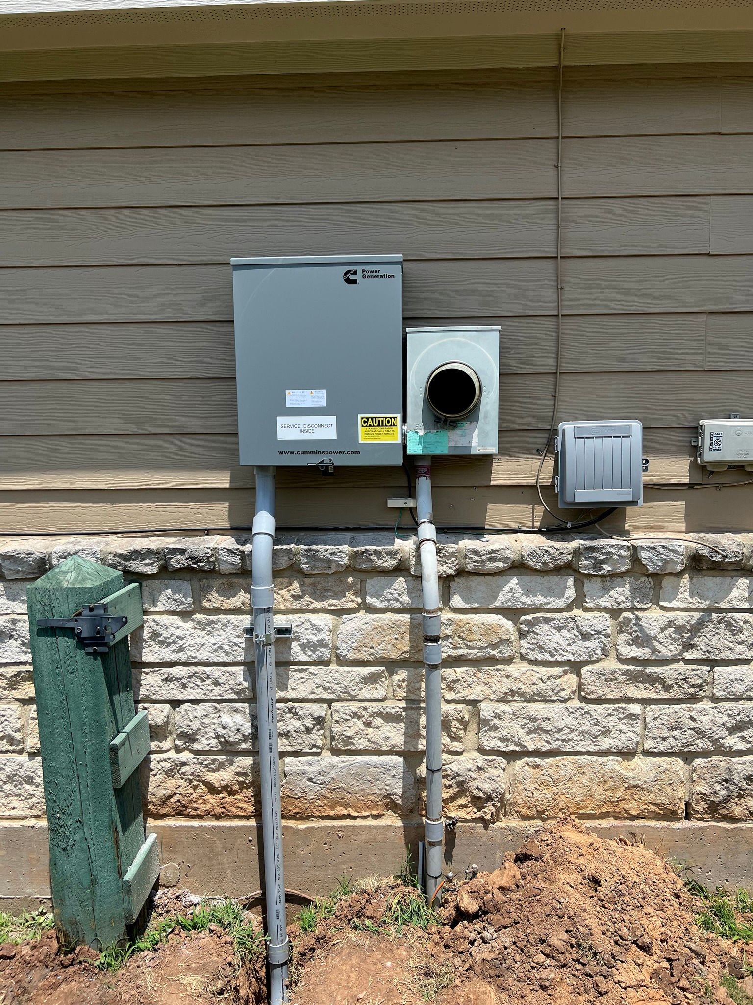 Electrical equipment on a beige brick wall with a meter box, conduit, and breaker box.
