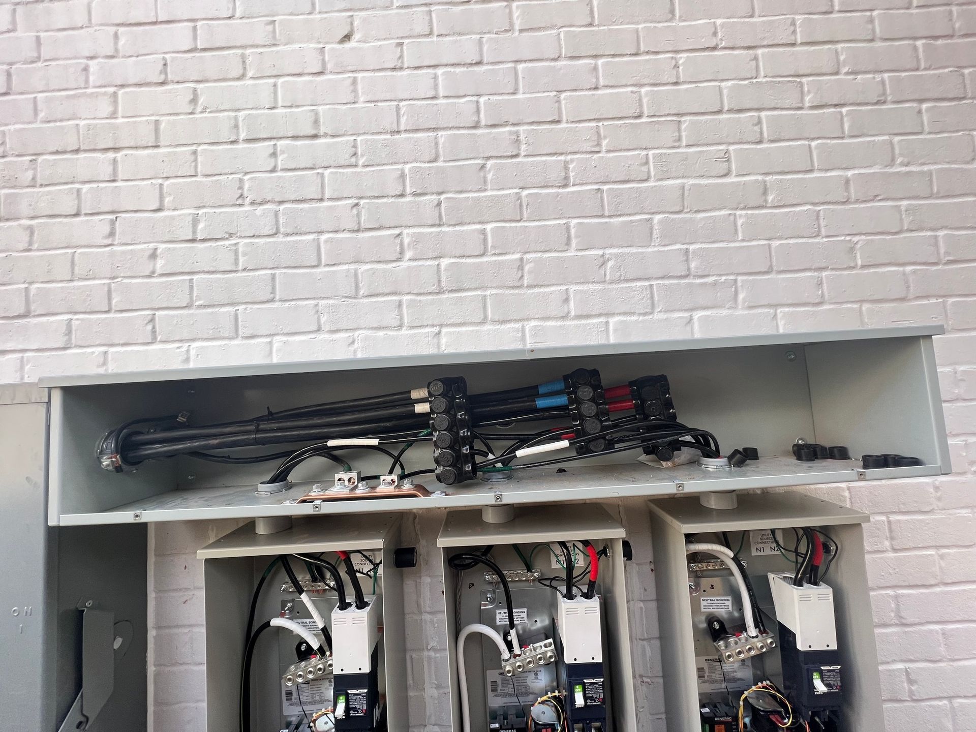 Electrical meter boxes mounted on a brick wall, with exposed wiring and conduits.