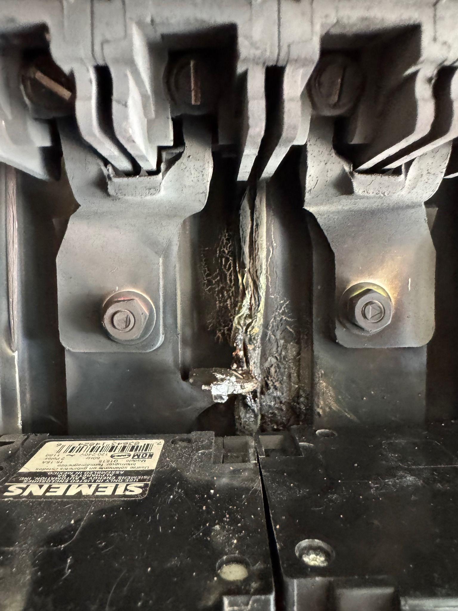Close-up of a damaged electrical circuit breaker, showing burnt residue and melted components.