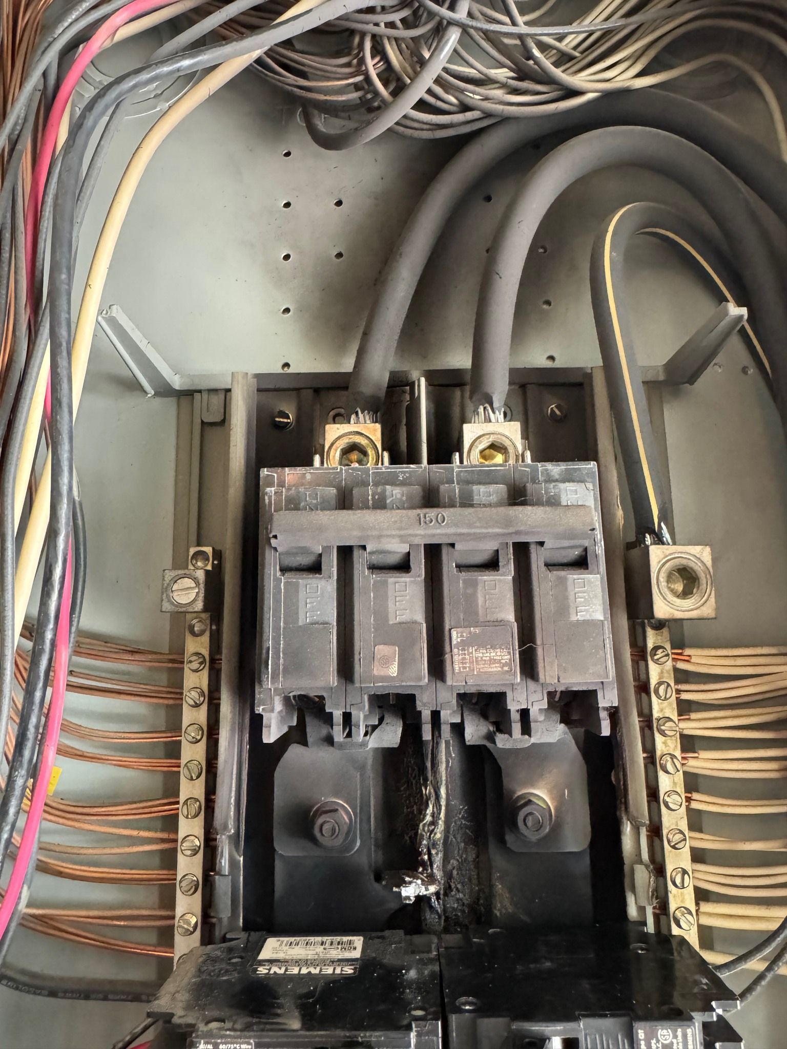 Electrical panel with burnt circuit breakers and wiring.