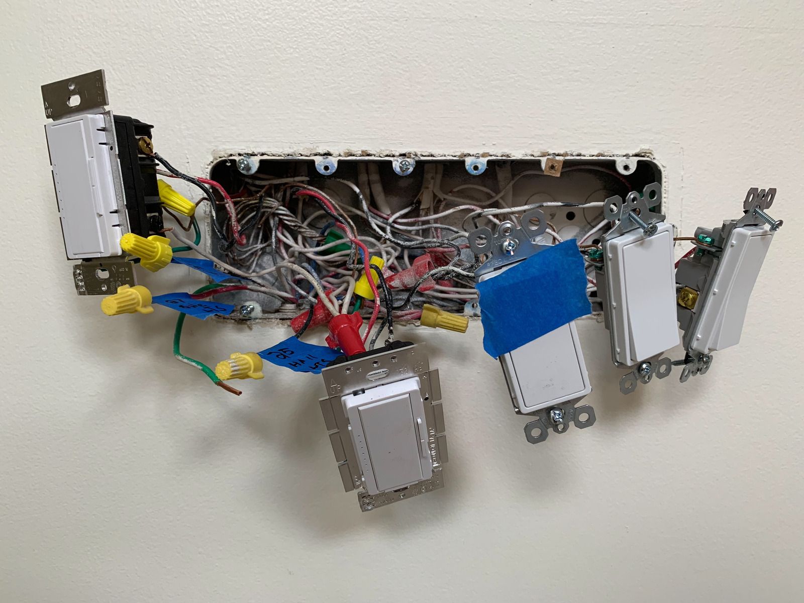 Electrical wires, various colors, connected with wire connectors, extending from a metal box.