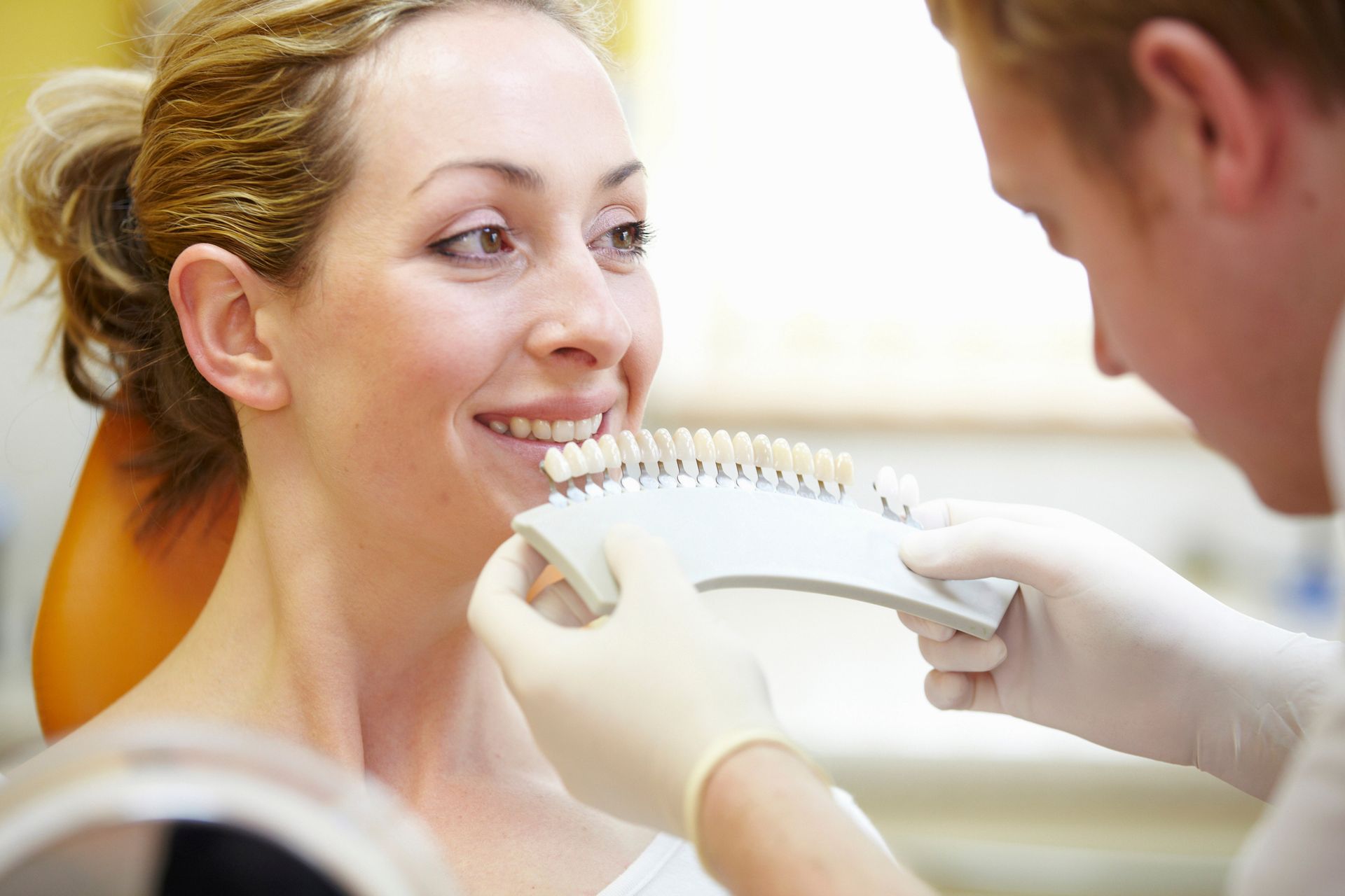 A dentist is using a tooth color palette on a patient.