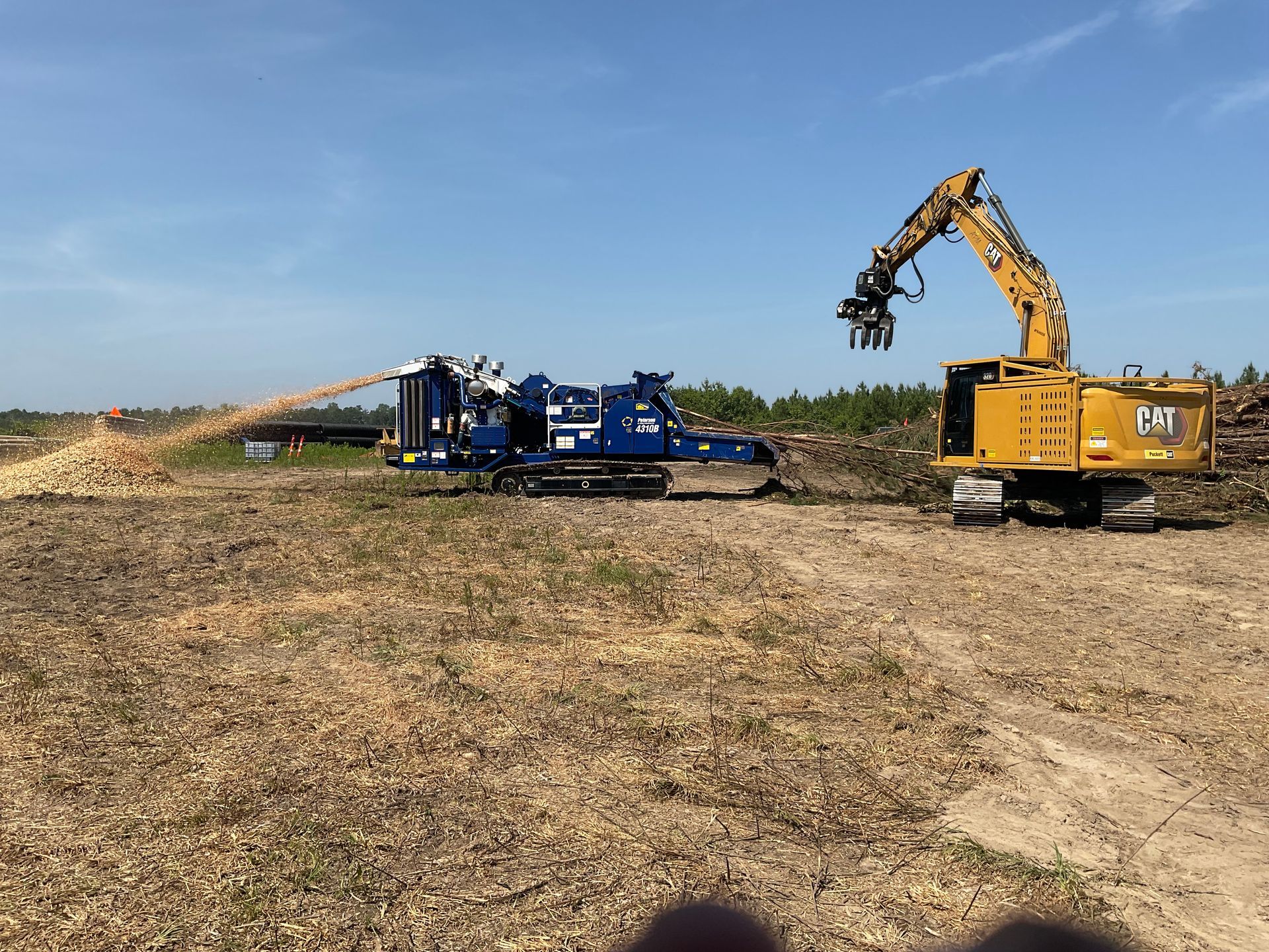 Construction equipment lined up on a dirt mound, preparing a site at dusk.