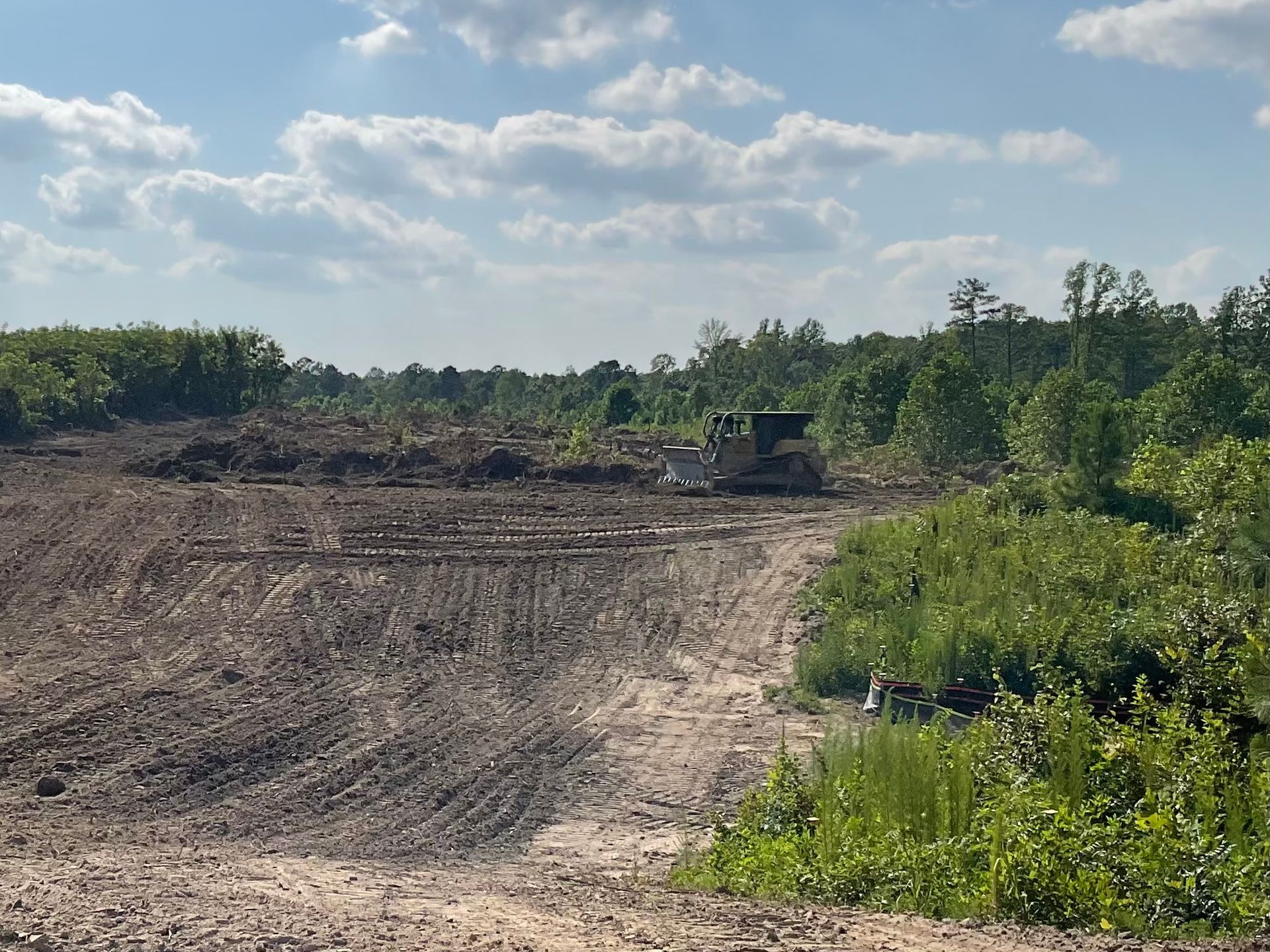 Construction site with smoke and power lines under a cloudy sky. Brown debris in foreground.
