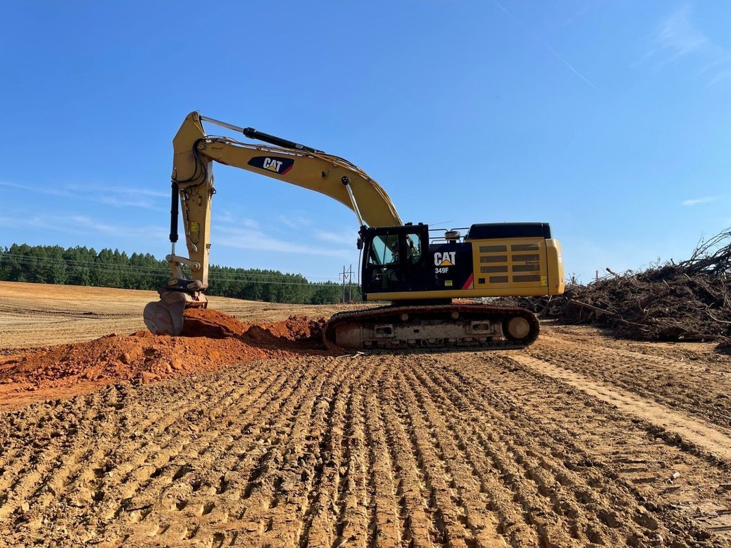 Yellow Caterpillar excavator working on a construction site under a clear blue sky.
