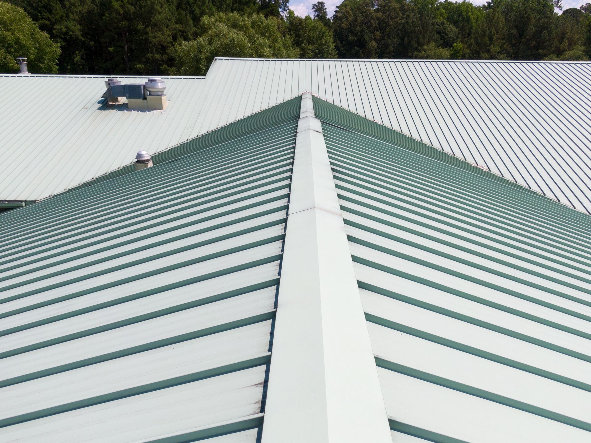 Green and White Metal Roof With Ridge and Trees in the Background — Hales Plumbing & Roofing In The Range, QLD