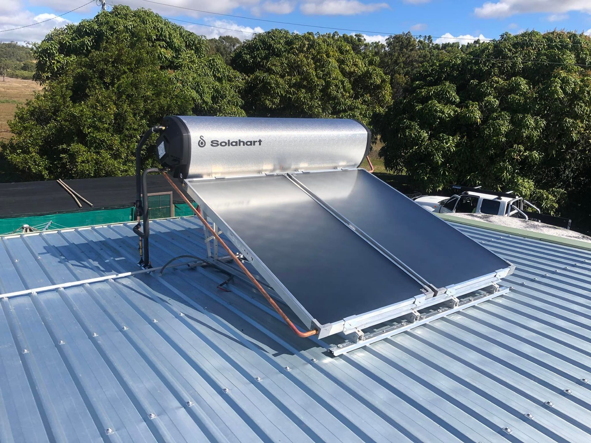 A Person's Hand Adjusting a Thermostat Dial on a White Water Heater — Hales Plumbing & Roofing In The Range, QLD